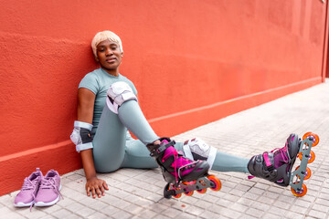 African urban woman sitting on the ground wearing inline skates
