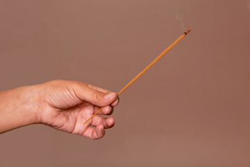 Hand holding burning incense stick. Relaxation and mindfulness concepts.