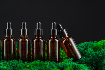 Dark glass bottles arranged in row on green moss against a black background