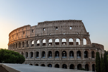 Sunrise over the Colosseum: The ancient Roman amphitheater is bathed in the soft, golden light of dawn, revealing its majestic silhouette against a serene morning sky.