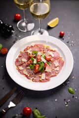 cooking tuna carpaccio - cherry tomato pieces on a plate with raw tuna fillet slices