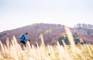 Obraz premium Active man on bike in the middle of beautiful nature, early autumn morning. Concept of healthy lifestyle.