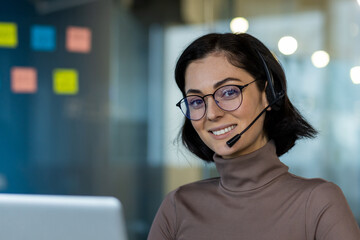 Confident customer service representative with headset and glasses smiling at camera. Engaged in...