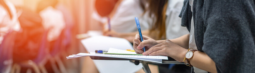 Exam at school with student's taking educational admission test in class, thinking hard, writing...