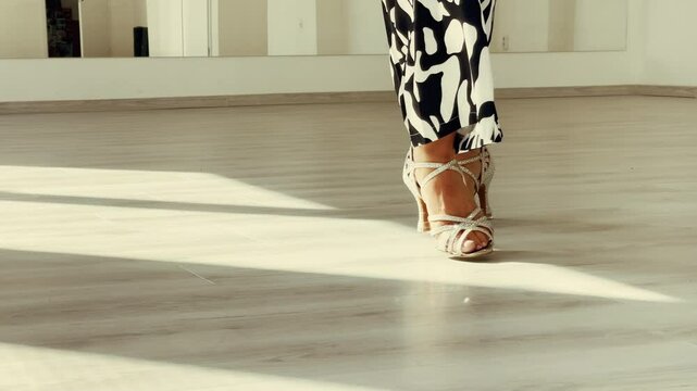 Graceful woman's legs in high heels shoes doing latin dance steps in elegant dancing big sunny hall. People's during dancing, beauty of woman's body concept 4K slow motion video.
