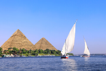 Famous Great Pyramids of Chephren and Cheops and traditional sailing boat felucca, Nile river,...