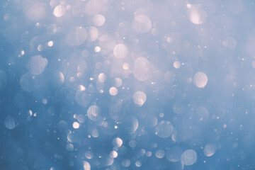 Blurred snowflakes in winter forest. Glowing bokeh abstract background.