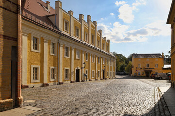 Naklejka premium Blick durch das Flurtor auf die gepflasterte Straße mit gelben Wohnhäusern und modernen Fassaden in der Altstadt von Grimma an der Mulde, Sachsen, Deutschland