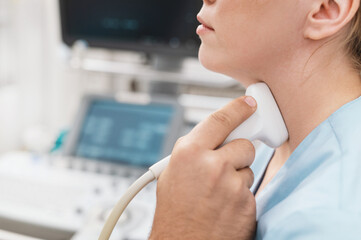 woman receiving thyroid diagnostics doctor's hand with sensor in rubber glove closeup. Treatment of...