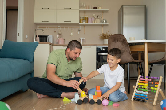 Happy boy with father sitting on floor and playing at home