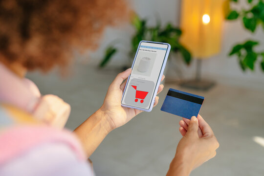 Woman holding smart phone and doing online payment with credit card at home