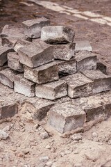 A stack of cobblestones for a sidewalk. Removed paving stones. Time to scatter and collect stones. Stone road. Repair works. Paving stones in a pile. Bricks under construction.