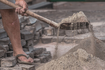 Obraz premium Industrial tool for repairing paving stones on the sidewalk. A man removes old cobblestones with a perforator. Drill, shovel, pickaxe and hammer on construction site. Road repair. Home tool.
