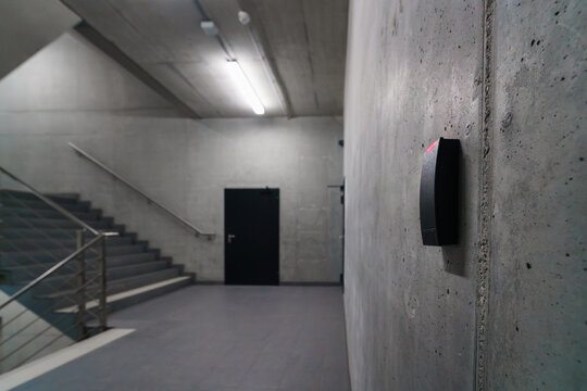 Access card reader gray concrete staircase wall. Office background real estate interior. Parking lot.