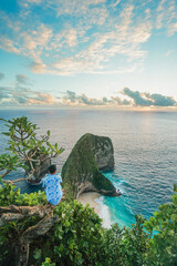 Young man traveller sit and look sunset at Klingking Beach, Nusa Penida, Bali, Indonesia. summer background and summer vacation concept. © Balnyes Visuals