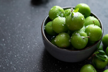 Green plum fruit in ceramic bowl on white background, fruit that pregnant women love