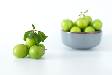 Green plum fruit in ceramic bowl on white background, fruit that pregnant women love