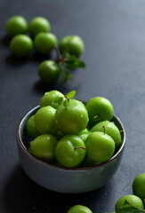 Green plum fruit in ceramic bowl on white background, fruit that pregnant women love