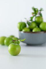 Green plum fruit in ceramic bowl on white background, fruit that pregnant women love