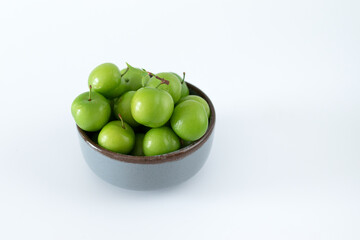 Green plum fruit in ceramic bowl on white background, fruit that pregnant women love