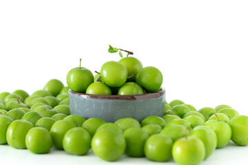 Green plum fruit in ceramic bowl on white background, fruit that pregnant women love