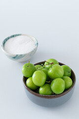 Green plum fruit in ceramic bowl on white background, fruit that pregnant women love