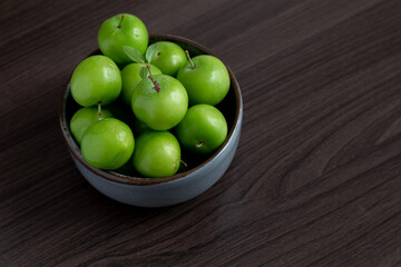 Green plum fruit in ceramic bowl on white background, fruit that pregnant women love