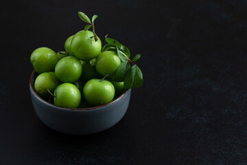 Green plum fruit in ceramic bowl on white background, fruit that pregnant women love