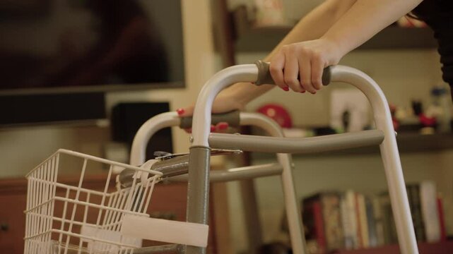 Woman hands pushing medical walker through living room