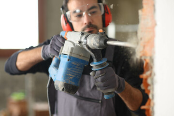 Construction worker wrecking wall using rotary hammer