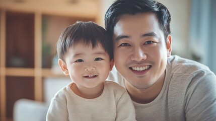 Portrait of Asian child and father happily looking at camera in warm home.