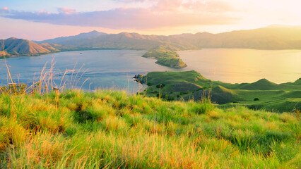 Beautiful tropical landscape with green hills at sunset in Gili Lawa in a morning sunrise, Komodo national park in Flores island, Indonesia. © Balnyes Visuals
