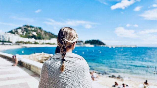 Woman on her back on the tourist beach of Blanes in the region of La Selva, Girona.