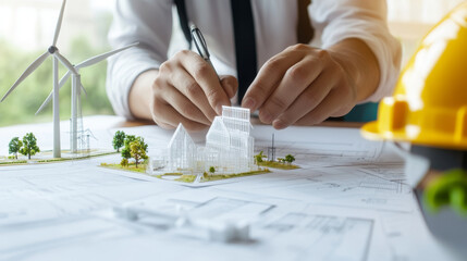 Close up of an engineers hand adjusting wind turbine model while working on architectural plans, showcasing innovation and sustainability in design