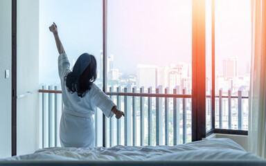 Hotel relaxation on lazy day morning with Asian woman waking up from good sleep, resting in comfort...