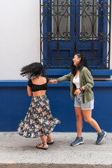 Two women laughing and twirling on a street in Santa Marta, Colombia