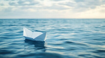 Obraz premium White paper boat floating on the open sea, with the serene water and horizon in the background.
