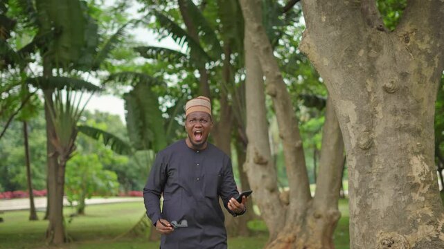 Man reacts to sad news on his phone as he removes his sunglasses, screams 'What?!' and shakes his head.