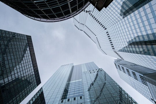 Perspective shot looking up at multiple glass skyscrapers against a cloudy sky, capturing the enormity and grandeur of urban development and modern architecture in London