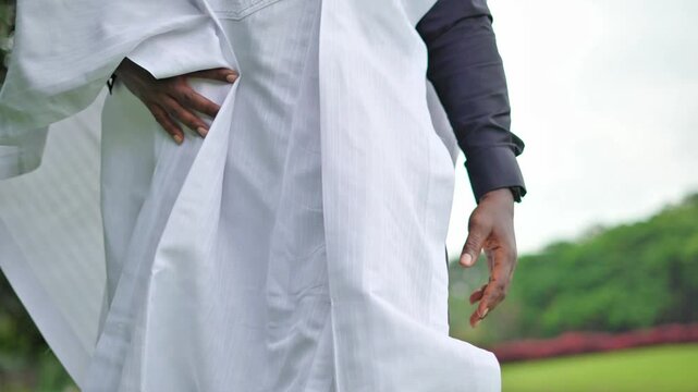A smiling African male in traditional attire smiling and walking outdoor towards the camera in a show of power, collaboration and diversity