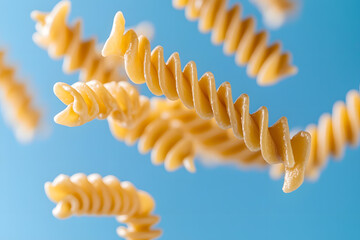 Dry pasta swirling in the air on blue background
