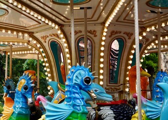 Carousel amusement park toy machine with seahorse and ostrich animal shaped ride isolated on horizontal ratio background.