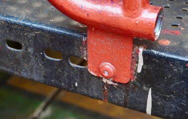 Heavy duty orange colored bolt metal connection on outdoor playground park toy fence and bridge equipment.