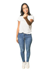 Fototapeta premium Full body shot of Latina in studio pointing with finger at you as if inviting come closer.