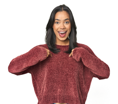 Simple portrait of a young Latina surprised pointing with finger, smiling broadly.