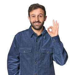 Studio portrait of young Hispanic male winks an eye and holds an okay gesture with hand.