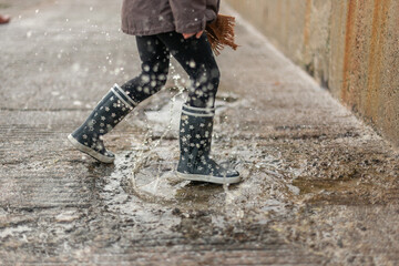 Child splashing in a puddle of rain near the beach