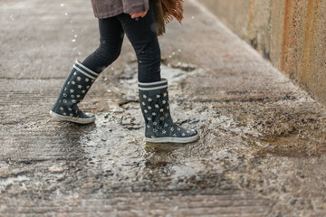 Child splashing in a puddle of rain near the beach