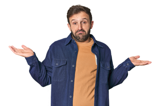 Studio portrait of young Hispanic male doubting and shrugging shoulders in questioning gesture.