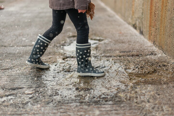 Child splashing in a puddle of rain near the beach